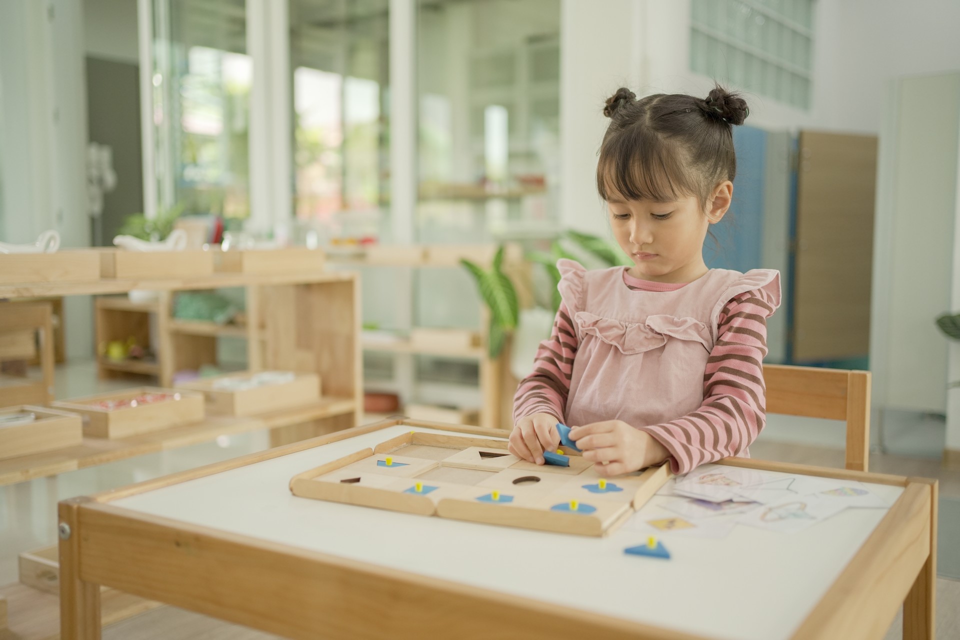 Preschool mixed girl learning about shape using geometric inset,